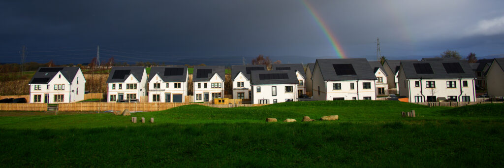 Row of new family homes under a rainbow in rural Scotland